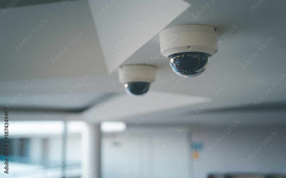 Obraz premium Ceiling mounted CCTV security camera in a modern indoor hallway for surveillance and continuous monitoring for safety crime prevention smart building technology and professional security systems.