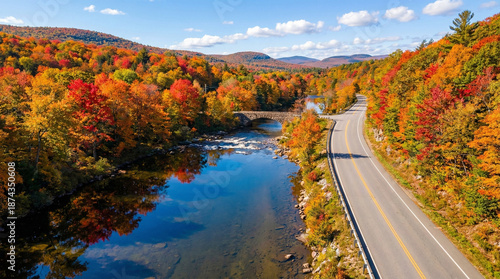 Scenic Autumn Highway Running Along Crystal Clear River Through Vibrant Fall Foliage Forest in New England Mountains