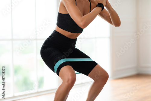 Wallpaper Mural Closeup cropped view of athletic sportswoman squatting with elastic resistance band in fitness studio or at home in living room. Lady enjoying leg and buttocks work out with equipment Torontodigital.ca