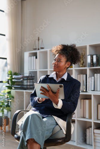 Fotografia African American businesswoman holding a digital tablet, sitting in a modern off