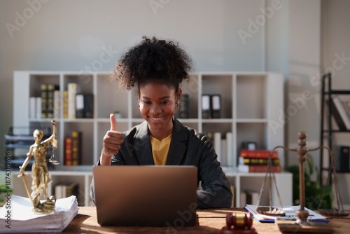 African American female lawyer provides online legal advice, smiling and giving a thumbs up gesture, reassuring clients after a successful virtual meeting