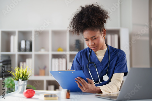 Konstfotografi African American female nurse wearing blue scrubs and a stethoscope, intently re