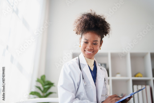 Φωτογραφία African American woman doctor smiling, wearing a white lab coat and stethoscope,