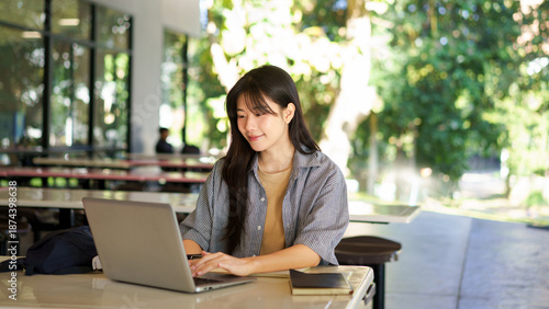 Education, university and woman in campus, research and books for school project or exam. Laptop, notebook and internet, college student studying with technology and e learning on campus