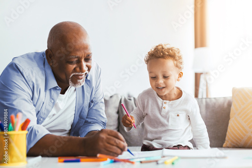 Canvas Print A grandfather and his grandson enjoy drawing on a couch