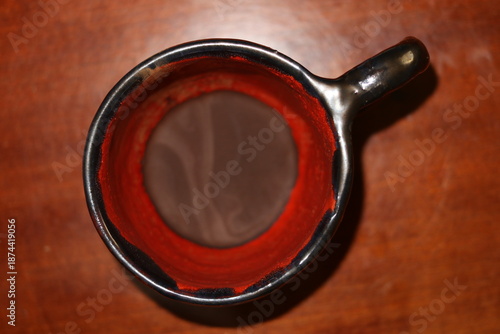 Red and black ceramic coffee cup with coffee grounds.
