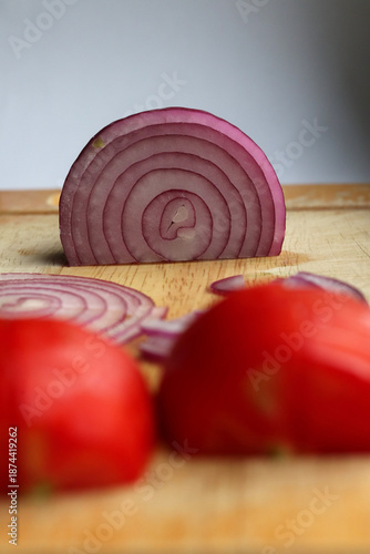 Sliced onion and sliced tomato on a cutting board.