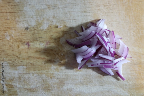 Sliced onions are placed on top of a wooden board.