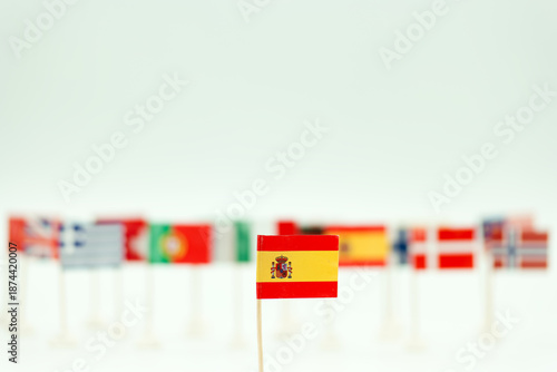 Flags from different countries displayed on small sticks with a focus on the Spanish flag in the foreground during a cultural event