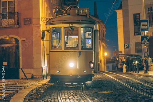 Foto Golden tram glides through narrow streets of Lisabona at dusk, illuminated by warm streetlights