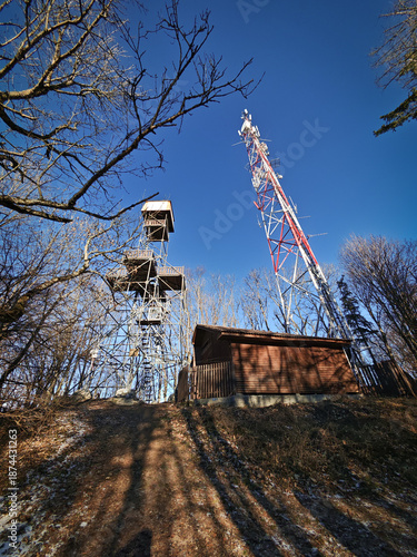 Petőfi Lookout Tower and a communication mast stand on Bálvány peak in the Bükk Mountains, Hungary. Popular hiking destination photographed on a clear winter day.