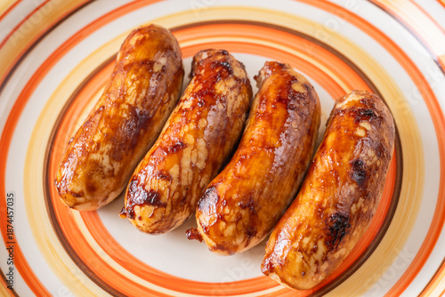 Glazed chicken sausages arranged on decorative plate with warm caramelized finish