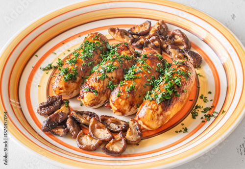 Glazed chicken sausages with herbs and mushrooms on decorative plate studio food