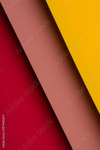 Colorful sheets of paper placed at an angle on a flat surface create a layered design with red, pink, and yellow colors
