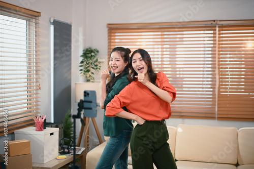 Two girl dancing and making videos for their blogs or social networks. Blogger filming vlog with online content.