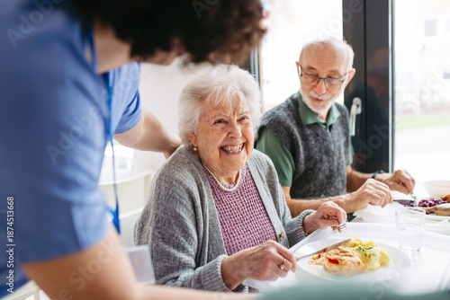 Fotografie Group of seniors having lunch in community center cafeteria.