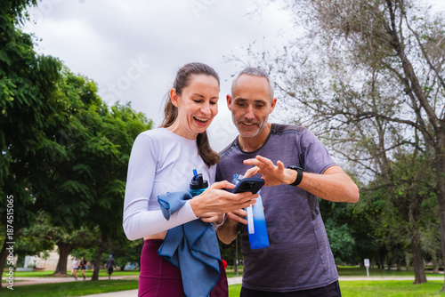 Two friends over forty checking health data on a smartphone after outdoor exercise