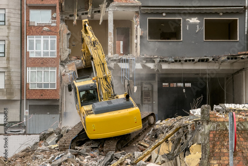 Fotografija yellow excavator clears the rubble of a residential building in Ukraine after it