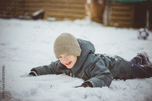 Boy playing with snow outdoors on winter day. Child enjoying winter nature, cold weather and seasonal outdoor activity.