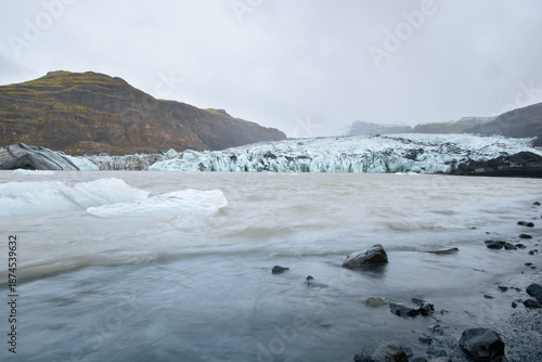 Majestic Icelandic glacier meeting a glacial lagoon with floating icebergs.