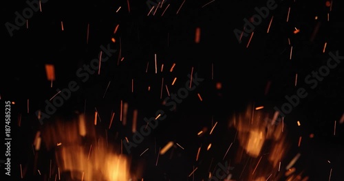 Fire and sparks at night close-up, slow motion. The flames of burning wood log fire on black background. Glowing sparks rising from burning firewood at night