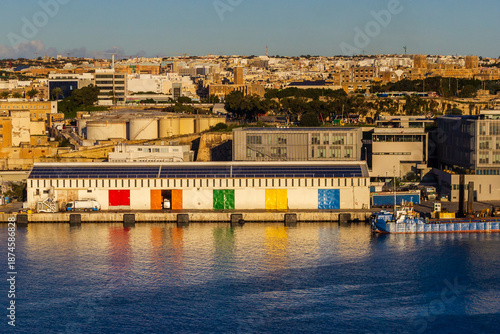 Tableau sur toile Colorful Waterfront Warehouse Doors Along Harbor With City Skyline At Sunset