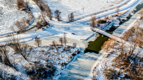 Winter scenery in the Spreewald region, Brandenburg, Germany, on a bright sunny day: snow-covered meadows and riverbanks along the River Spree and its canals, frozen waterways under a clear blue sky, 