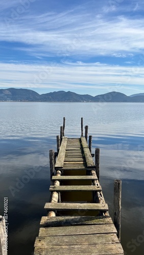 A beautiful view of a lake, with a wooden bridge.