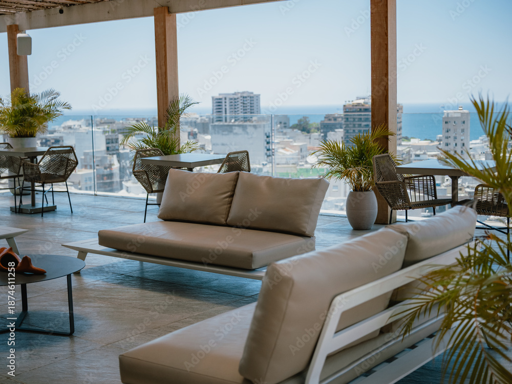 Fototapeta premium Relaxation area on terrace with sofas, plants and urban ocean view from rooftop