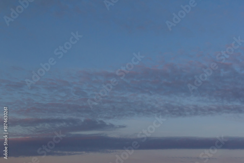A tranquil dusk scene features a blue sky, wispy cloud cover, and a calm hori...