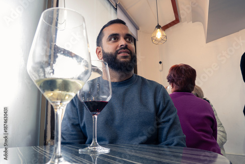 Chico joven tomando una copa de vino en un bar