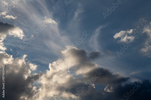 Expansive blue sky with fluffy clouds and soft sunlight. A calm, open mood id...