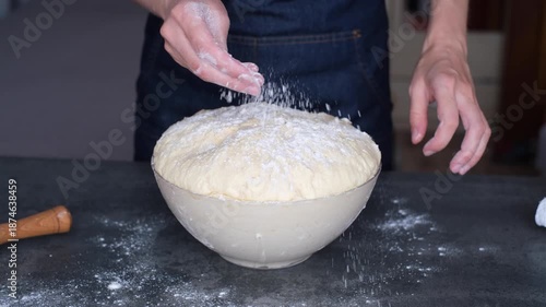 A person is covering a bowl filled with dough using a towel. The bowl sits on a kitchen counter. The dough has risen, showing signs of fermentation.