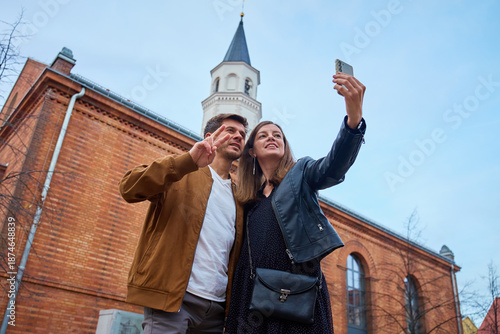 Couple taking selfie with smartphone near brick building