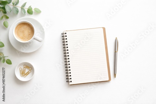 Minimal flat lay of a study workspace featuring a spiral notebook, pen, coffee cup, and small decorative elements on a clean neutral background. Natural daylight, clean and organized composition ideal