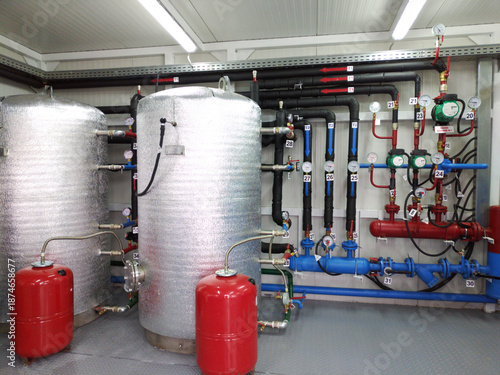The interior of a modern gas boiler room. Visible are the pipes for supplying cold and hot water, large tanks, and numerous valves for shutting off the gas and liquid supply.