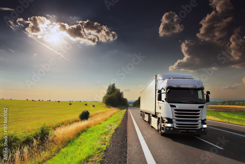 Large Transportation Truck on a highway road through the countryside at sunset
