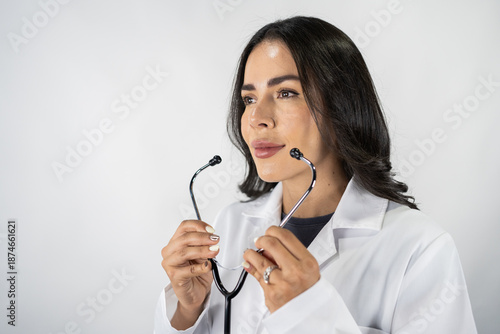 Female doctor holding stethoscope looking away on white background