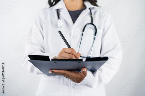 Close-up of doctor writing patient report on clipboard