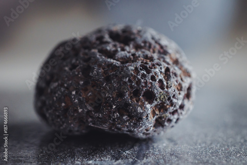 Close up of a dark, porous volcanic scoria rock showing vesicular texture