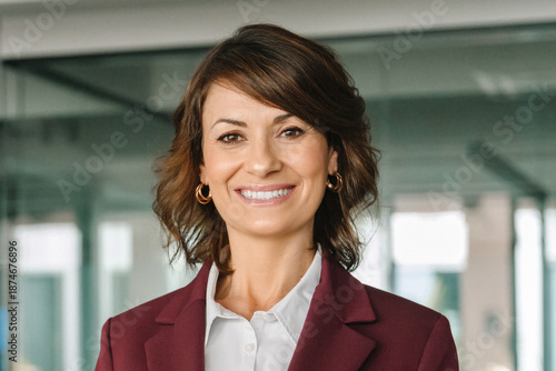 European confident mature middle aged leader female businesswoman manager standing in office. Closeup headshot portrait 40s latin hispanic senior business mentor coach woman leader smiling at camera