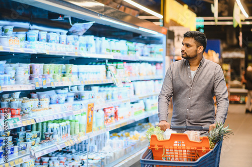Fotografie Man shopping for groceries in supermarket dairy aisle