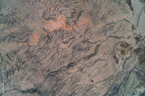 Abstract gray clay texture with orange rust mineral deposits and erosion cracks, quarry background aerial top down view