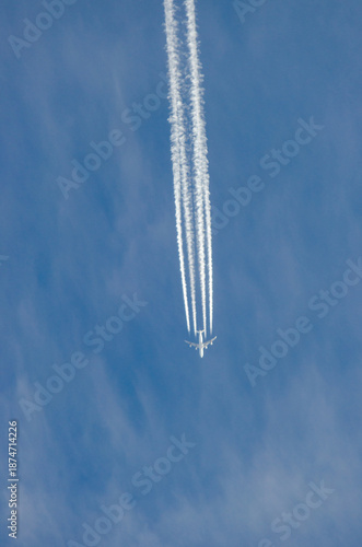 Large Jet Aircraft Flying Over Blue Sky Leaving Four Contrails