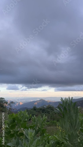 Peaceful Mountain Landscape at Sunset with Dramatic Cloudy Sky and Lush Green Foliage