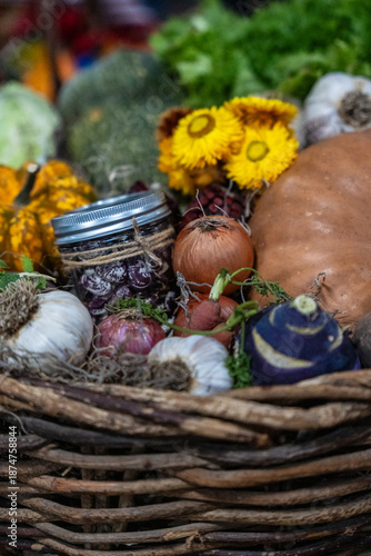 Fresh vegetables and herbs in a basket with flowers at a local market during autumn