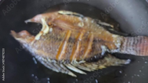 Blurred Frying sun-dried fish in pan, indoor Chiangmai Thailand.