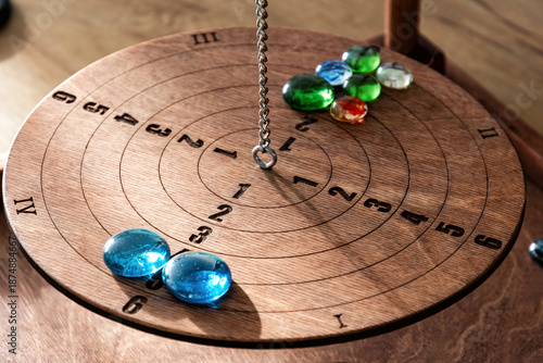 Close-up of a vintage wooden balance board game. Colorful glass marbles, engraved numbers, and a chain symbolize strategy, decisions, and precision