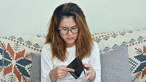 Asian woman having stress while she try to finding money in her empty wallet. Having financial problems means being unable to pay debts over the short or long term.