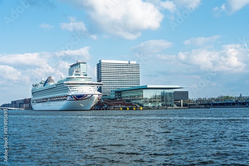 Photography Discover Amsterdam s charm with a scenic view of a grand cruise ship by modern architecture under a bright sky